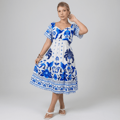 Vestido curto feminino com estampa tropical azul e branca, decote coração e mangas curtas. Possui elástico na cintura e modelagem soltinha com caimento fluido. Ideal para dias quentes, passeios ou ocasiões informais com estilo e frescor.