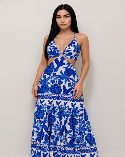 Modelo elegante de cabelos lisos pretos usando o Vestido Longo Floral Azul com decote profundo em V e recortes laterais. A peça apresenta estampa floral rica em detalhes e fundo branco. Fotografia com fundo neutro, realçando o caimento e o design da peça – coleção Verão da Fernanza.