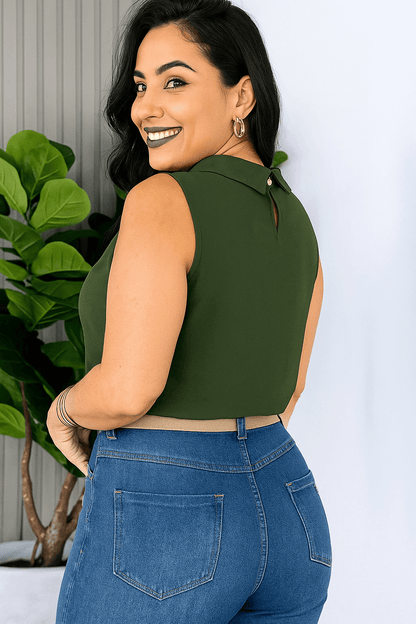 Mulher sorridente usando blusa social feminina verde militar, sem mangas, gola alta e detalhe plissado. Combinada com calça de alfaiataria preta e cinto verde escuro com fivela redonda trançada. modelo de lado Look sóbrio e elegante.