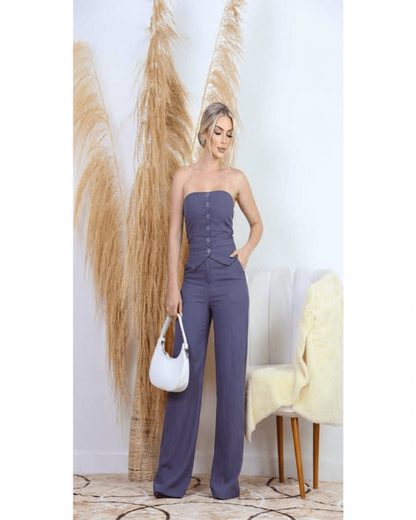 Mulher usando conjunto feminino elegante na cor cinza arroxeado, composto por calça pantalona de cintura alta e blusa tomara que caia com botões frontais e detalhe de recorte alfaiataria. Look sofisticado e moderno, ideal para eventos, trabalho ou ocasiões especiais.