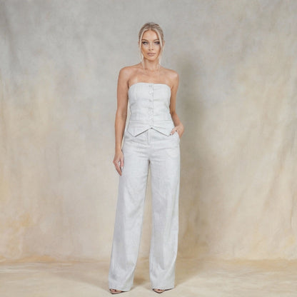 Conjunto Feminino Calça Pantalona com Blusa Tomara que Caia – Elegância e Versatilidade para Todas as Ocasiões | Fernanza. Look branco sofisticado com blusa tomara que caia estruturada, botões forrados e recorte tipo corset que valoriza o busto. A calça pantalona de cintura alta tem corte reto e caimento leve, ideal para produções clean, casuais elegantes ou eventos com dress code mais refinado.